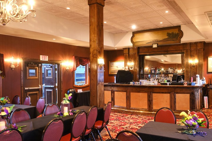 Elegant bar in a decorated room with red chairs and tables set for an event.