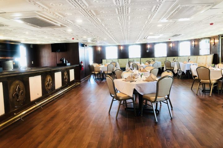 Elegant dining room with set tables, chairs, and decorative ceiling and walls.