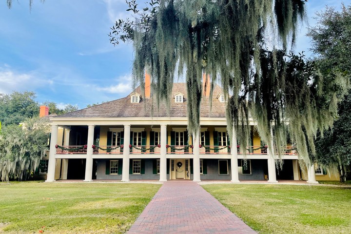 Large historic house with columns and hanging moss, fronted by a brick path.
