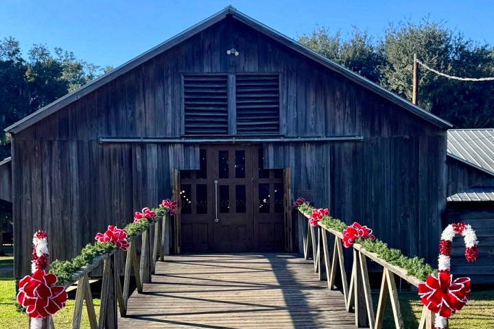 Rustic barn decorated with Christmas garlands and red bows on a sunny day.