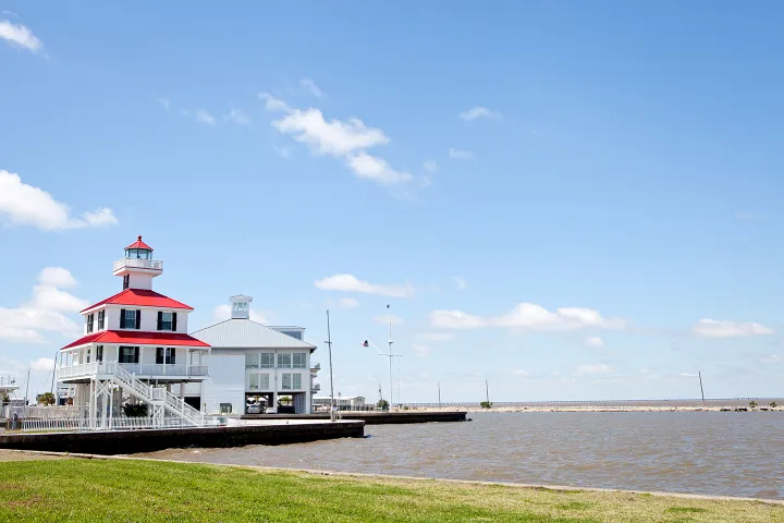 White building with red roof by a lake, clear blue sky.