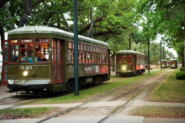 Streetcars on St. Charles Avenue with passengers, surrounded by trees.