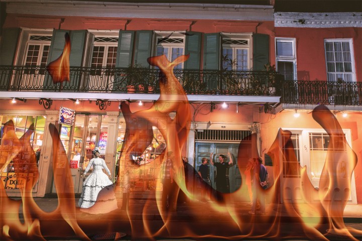 Flames overlay on a nighttime street scene with people standing and shops visible.