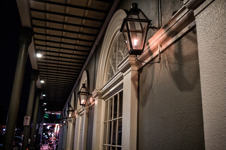 Night view of a building facade with gas lanterns and arched windows.