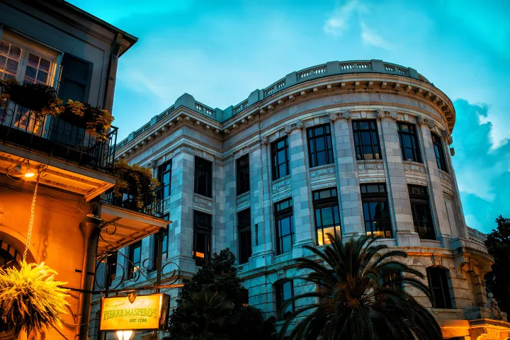 Illuminated historic building with columns at dusk, palm trees in foreground.