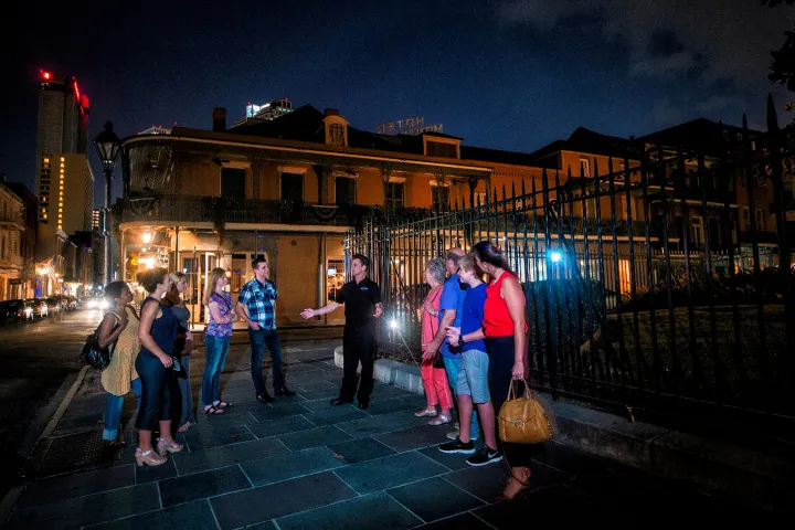 Group of people on a nighttime walking tour outside a historic building.