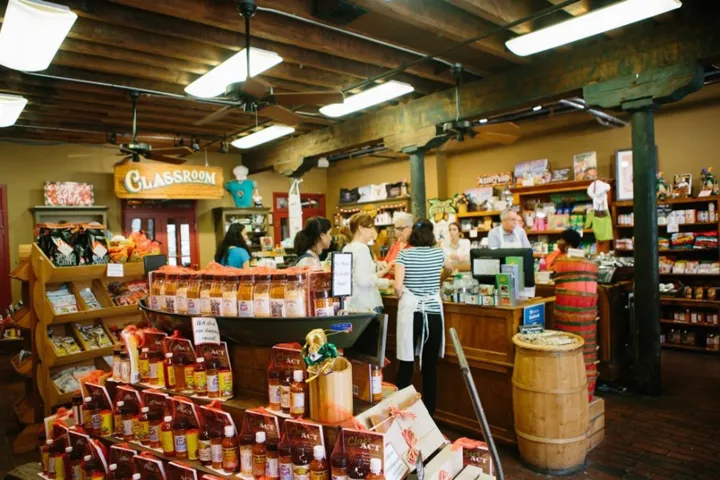 Busy market interior with people shopping and various products displayed.