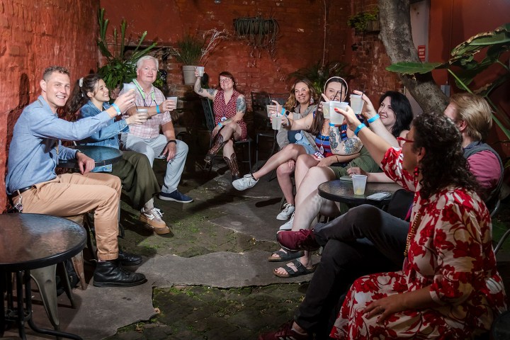 Group of people sitting outdoors, raising glasses in a toast.