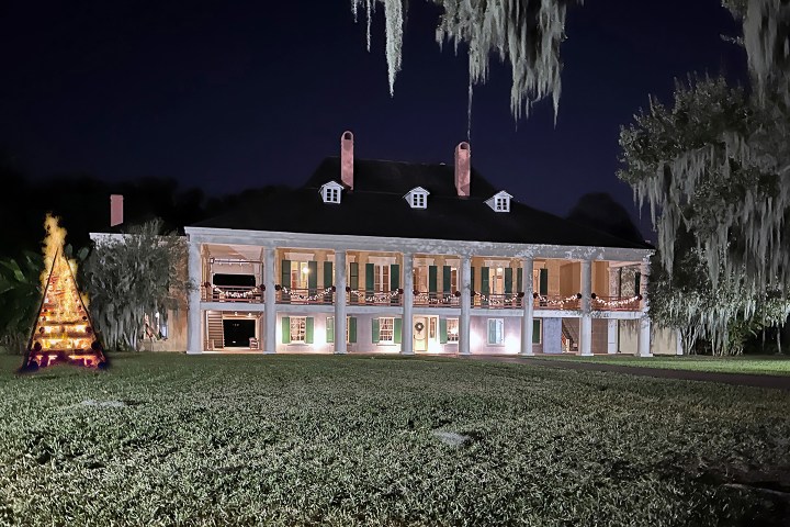 Illuminated mansion with Christmas lights and a decorative tree at night
