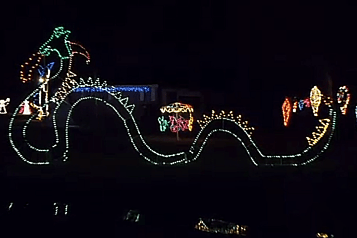 Christmas lights form a colorful sea serpent and other holiday figures on a dark background.