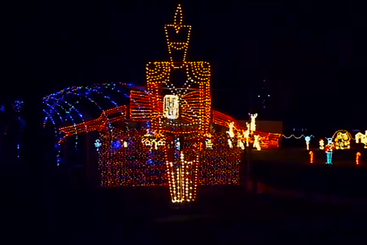 Festive light display with large nutcracker figure and colorful lights at night.