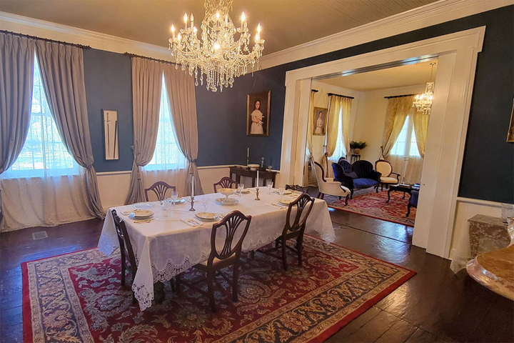 Elegant dining room with table, chairs, chandelier, and adjoining living area with seating.