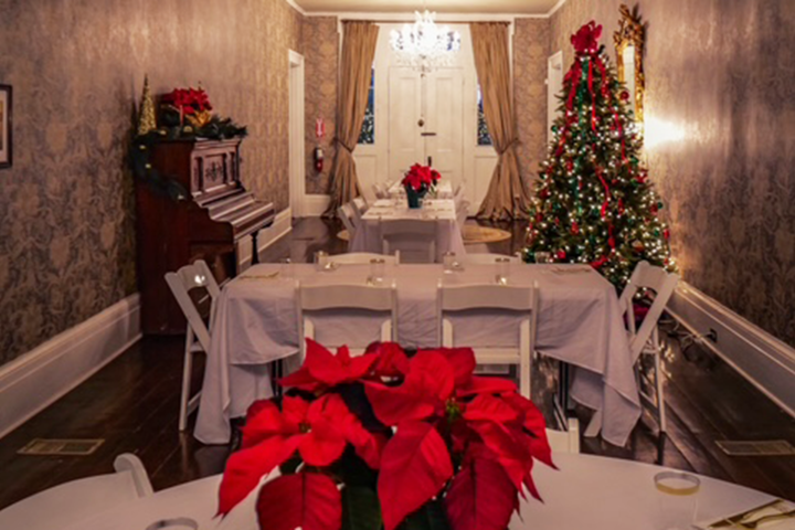 Festive dining room with poinsettias, a decorated Christmas tree, and a piano.