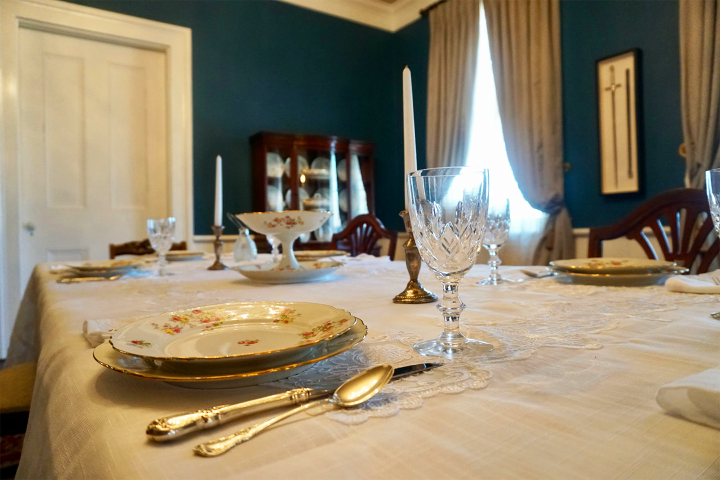 Elegant dining table set with china, glassware, and candlesticks in a formal dining room.