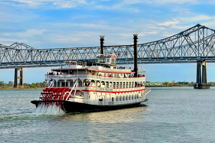 Paddle steamboat on a river with a bridge in the background.