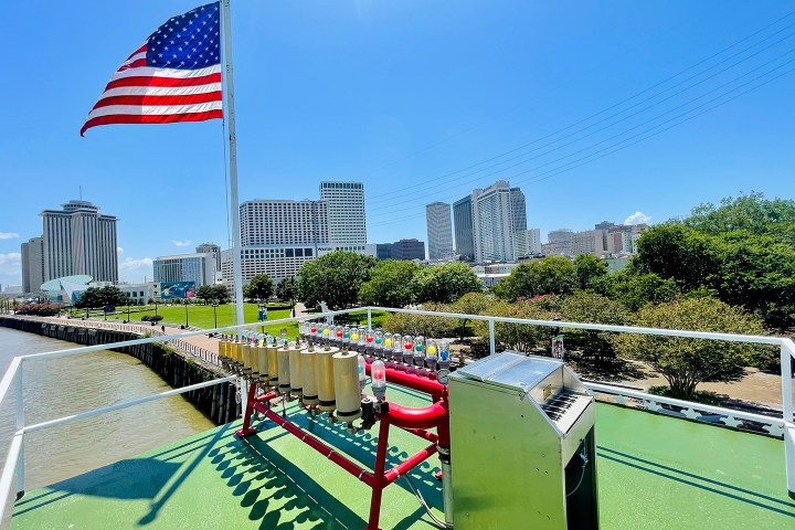 American flag on a boat with a city skyline and river in the background.