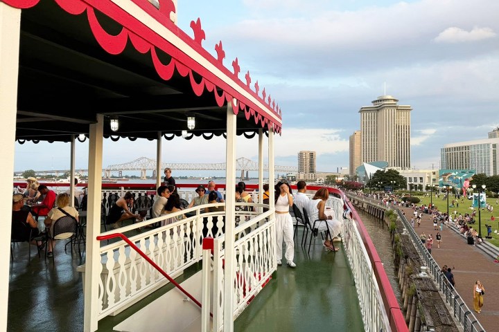 People relaxing on a boat deck with cityscape and bridge in the background.