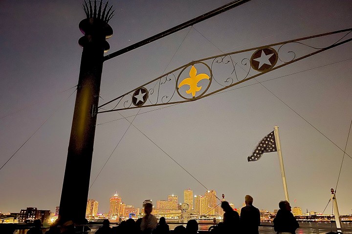 Silhouetted people against city skyline at night, with flag and fleur-de-lis decoration.