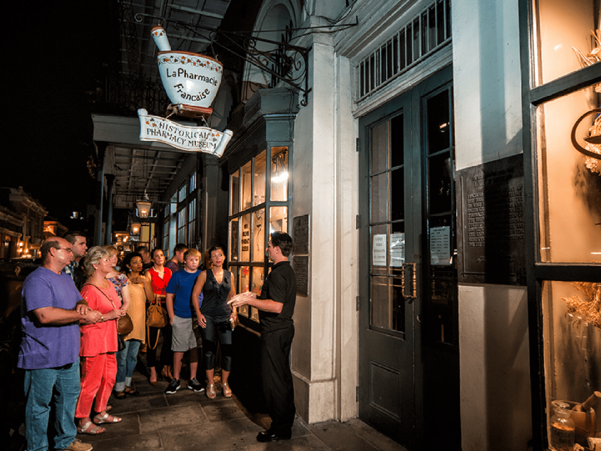 Group of people on a night tour outside a historic pharmacy.