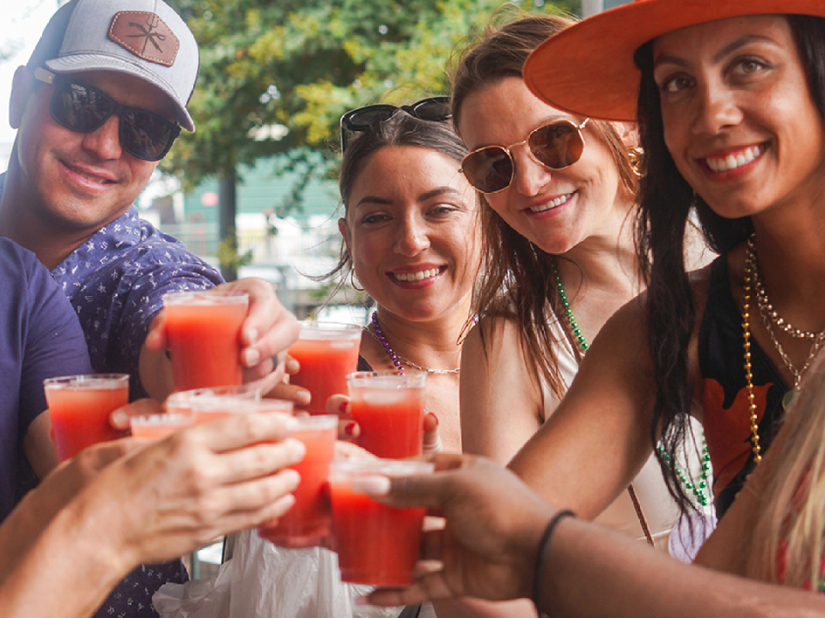 Group of people toasting with red drinks outdoors.