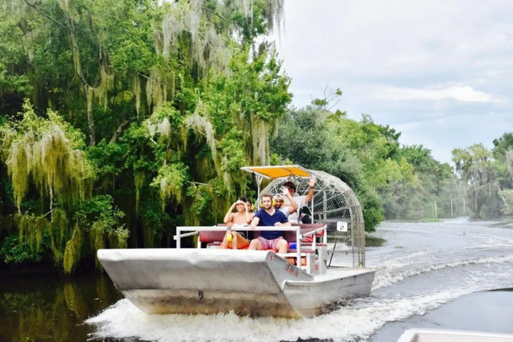 Airboat with people in a swampy area surrounded by trees.